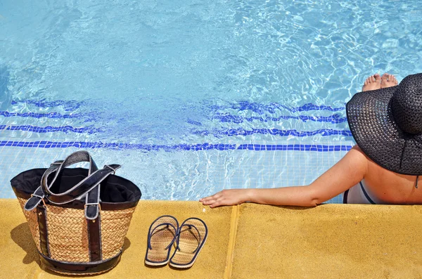 Mujeres con pamela en posición relajada en la piscina con bolsa y sandalias —  Fotos de Stock
