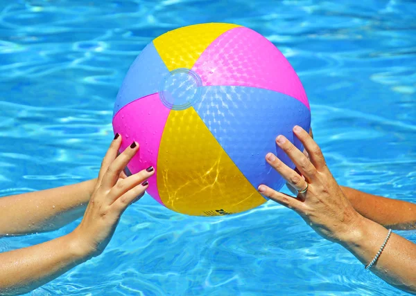 Руки матери и дочери играют с разноцветным пляжным мячом в плавании — стоковое фото
