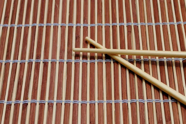 Baguettes japonaises sur fond de napperon en bambou — Photo
