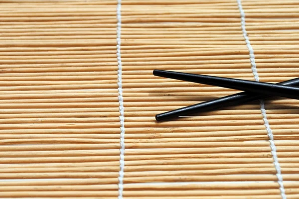 Palillos japoneses sobre fondo mantel de bambú —  Fotos de Stock