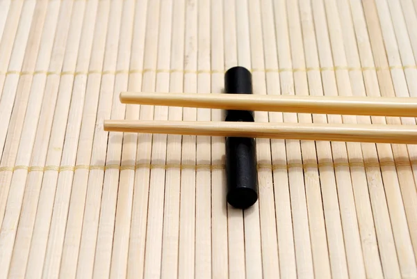 Palillos japoneses sobre fondo mantel de bambú — Foto de Stock