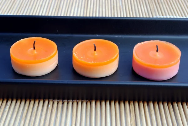 Velas de laranja em prato preto em bambu — Fotografia de Stock