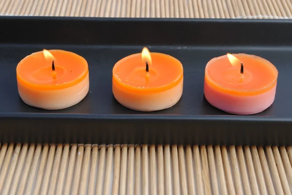 Candele arancioni in piatto nero su bambù — Foto Stock