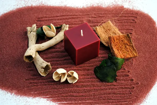 红色蜡烛用棍棒和鲜花的沙子上 — 图库照片