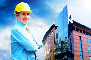 Young architect wearing a protective helmet standing on the buil clipart