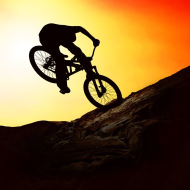 Silhouette of a man on muontain-bike, sunset clipart
