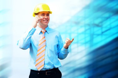 Young architect wearing a protective helmet standing on the buil clipart