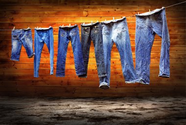 Jeans on a clothesline to dry on the grunge background clipart