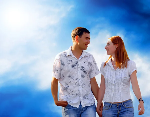 Mladá láska pár usmívá pod modrou oblohou — Stock fotografie