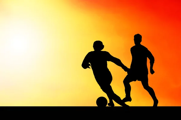 Napnyugtakor ég a labdarúgók sziluettek — Stock Fotó