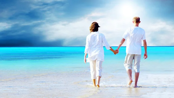 一对情侣手牵着手在海滩上散步的后视镜. — 图库照片