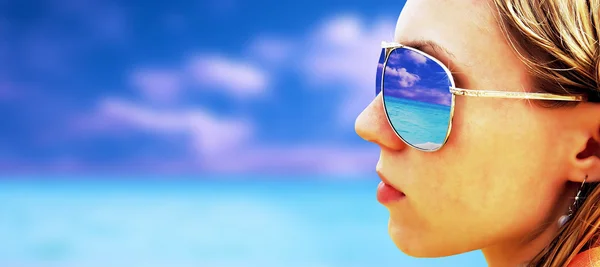 Молодая девушка в очках смотрит на тропический пляж — стоковое фото