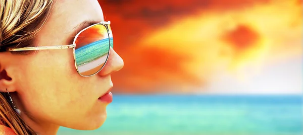 Ung pige i briller kigger på den tropiske solstrand - Stock-foto