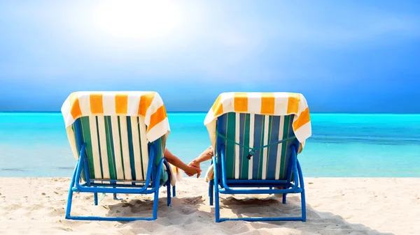 Nézet hátulról egy pár egy nyugágy, pihentető a strandon — Stock Fotó