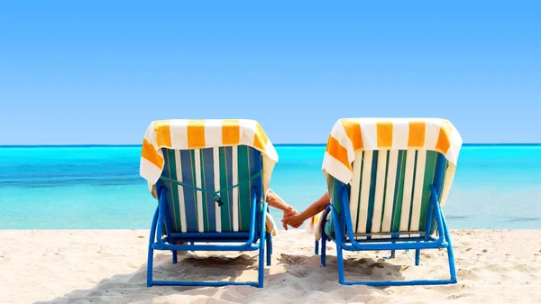 Achteraanzicht van een paar op een ontspannen ligstoel op het strand — Stockfoto