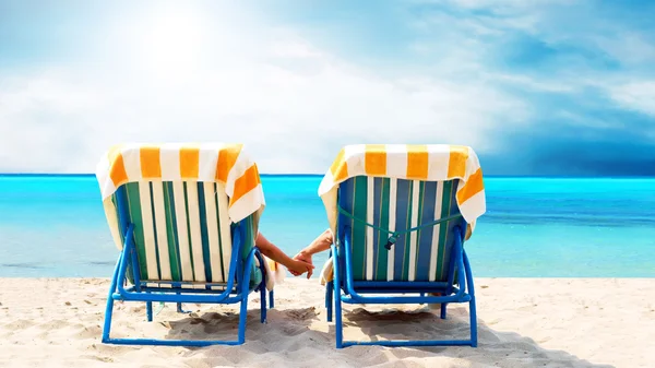 Vista trasera de una pareja en una tumbona relajante en la playa — Foto de Stock