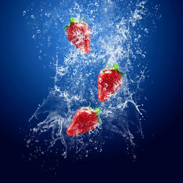 Wassertropfen um Erdbeere und Eis auf blauem Hintergrund — Stockfoto