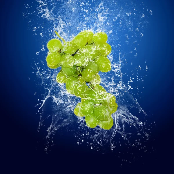 Kapky vody kolem zelené hrozny na modrém pozadí — Stock fotografie