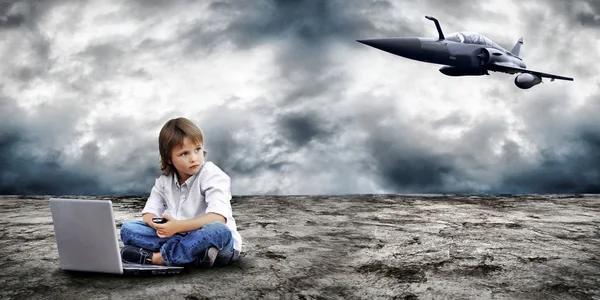 Young boy seating with notebook on the land and military plane