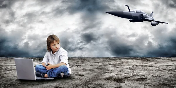 stock image Young boy seating with notebook on the land and military plane