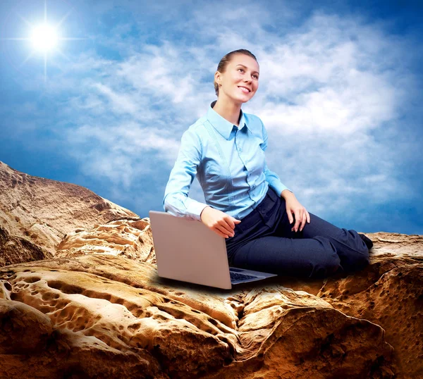 Glad affärskvinna sittplatser med laptop på berget under bl — Stockfoto