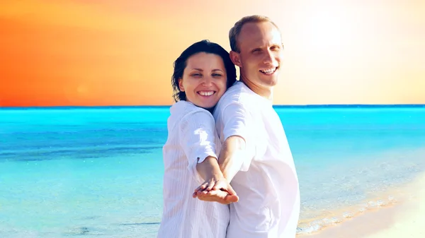 View of happy young couple walking on the beach, holding hands. — Stock Photo, Image