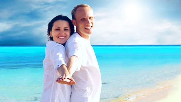 Вид счастливой молодой пары, идущей по пляжу, держась за руки . — стоковое фото