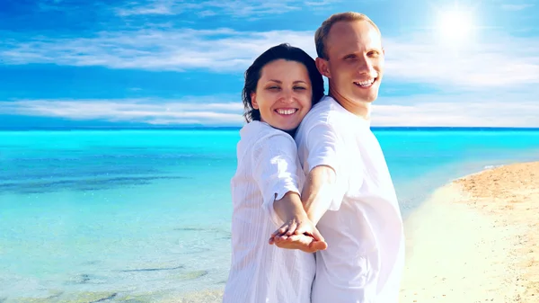 Vista de feliz jovem casal andando na praia, de mãos dadas . — Fotografia de Stock