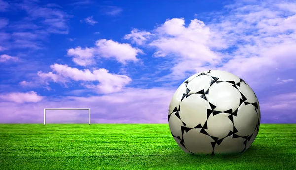 Pelota de fútbol sobre hierba verde y fondo del cielo — Foto de Stock