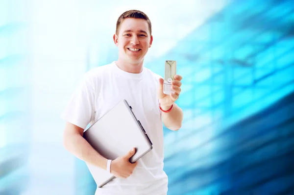 Χαρούμενος νεαρός ή φοιτητής με φορητό υπολογιστή και το τηλέφωνο για την επιχείρηση — Φωτογραφία Αρχείου