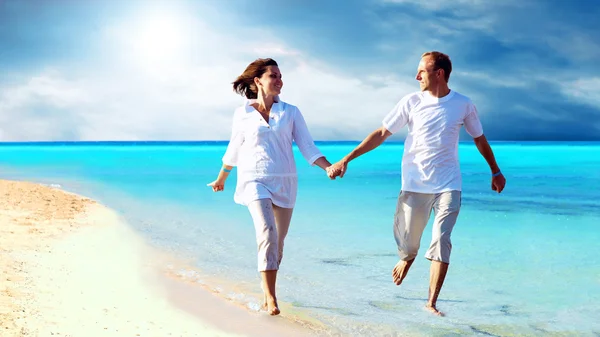 Vue d'un jeune couple heureux marchant sur la plage, se tenant la main . — Photo
