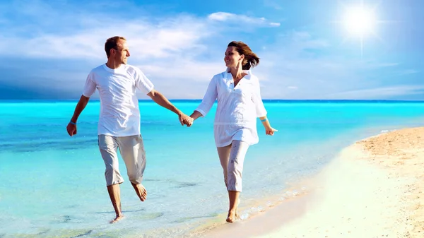 幸せなカップル、ビーチの上を歩いて手を繋いでいるのビュー. — ストック写真