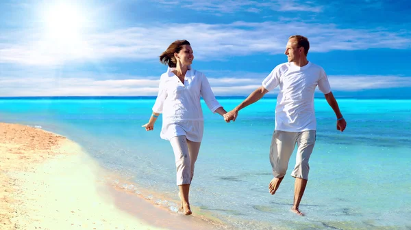 Visa lyckliga unga paret promenerar på stranden, hand i hand. — Stockfoto