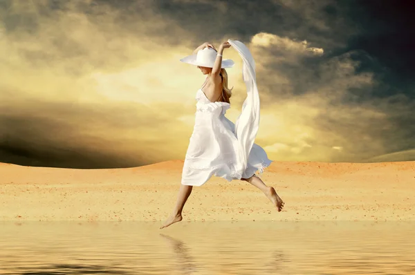 Jovens mulheres bonitas em branco, saltar sobre a água na deser ensolarado — Fotografia de Stock