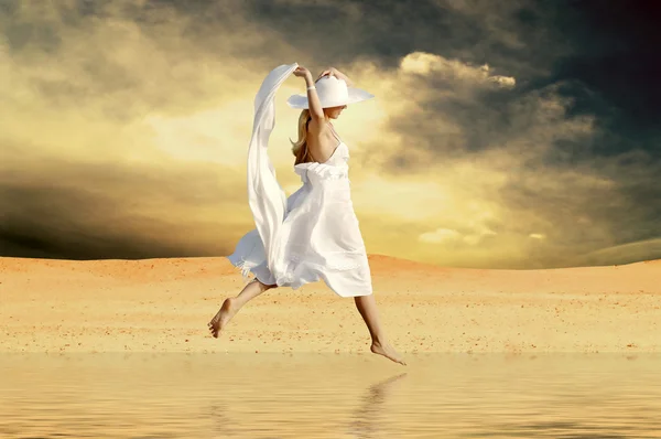 Jovens mulheres bonitas em branco, saltar sobre a água na deser ensolarado — Fotografia de Stock