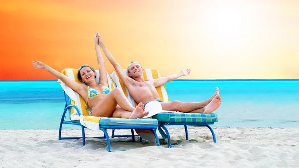 Bakifrån av ett par på en avkopplande solstol på stranden — Stockfoto