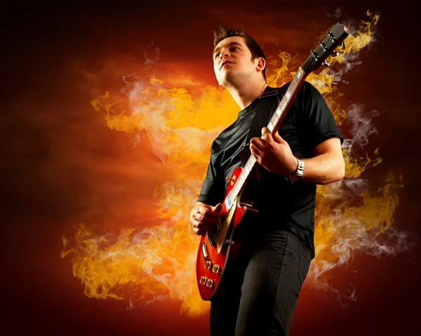 Rock guitarist play on the electric guitar around fire flames — Stock Photo, Image