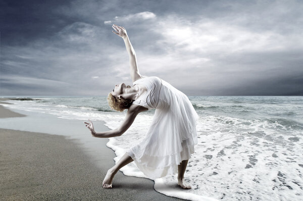 Woman dancer posing on the beach