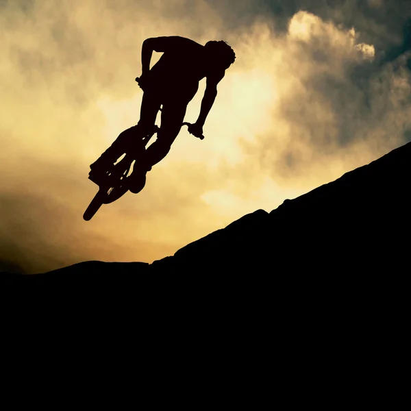 La silueta de un hombre en moto de montaña, puesta de sol — Foto de Stock