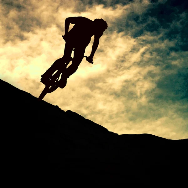 La silueta de un hombre en moto de montaña, puesta de sol — Foto de Stock