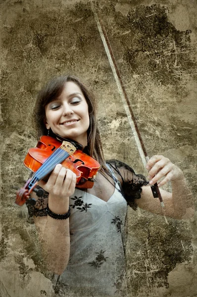 Beautiful female violinist playing violin on the grunge backgrou — Stock Photo, Image