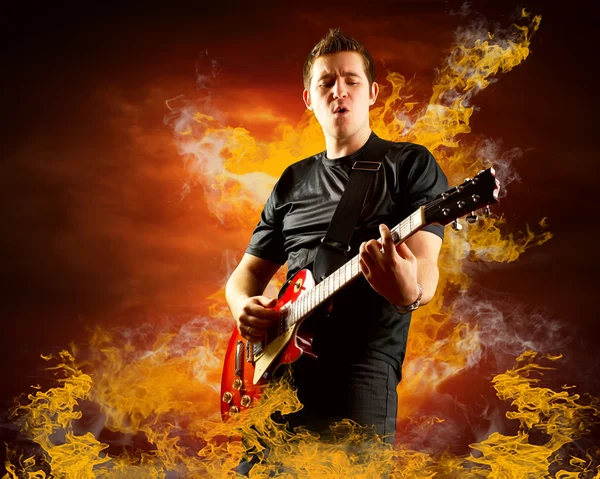 Rockový kytarista hrát na elektrickou kytaru kolem plameny ohně — Stock fotografie