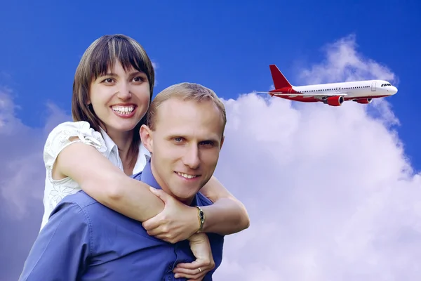 Feliz casal no céu azul com fundo de avião — Fotografia de Stock
