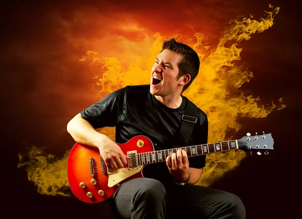 Guitarrista de rock toca en la guitarra eléctrica alrededor de llamas de fuego — Foto de Stock