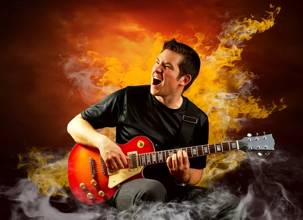 Guitariste rock jouer sur la guitare électrique autour des flammes de feu — Photo
