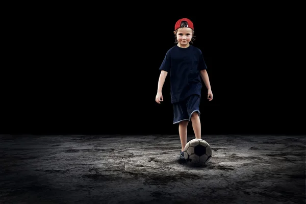 Jogador de futebol infantil e bola Grunge no fundo escuro — Fotografia de Stock