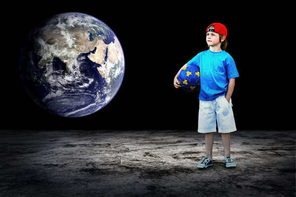 Child football player and Grunge ball on the dark background