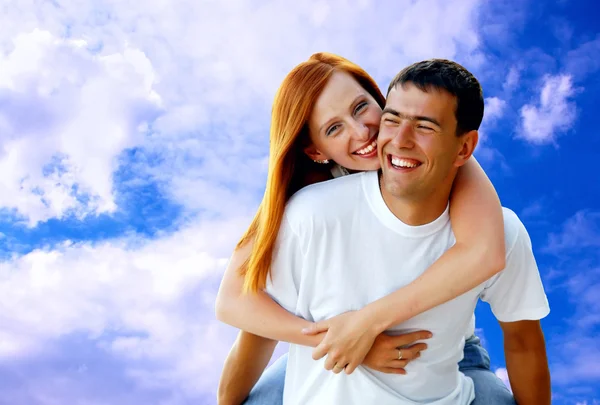 Fiatal szerelmes pár mosolygó kék ég alatt — Stock Fotó