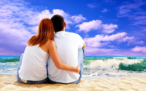 Vista mar de um casal sentado na praia . — Fotografia de Stock
