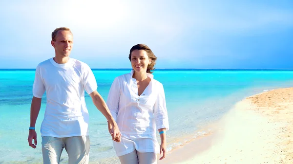View of happy young couple walking on the beach, holding hands. — Stock Photo, Image